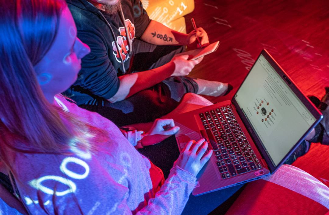 Ohjelmistokehityksen hinta -blogin kansikuvassa kaksi henkilöä katsoo läppäriä.